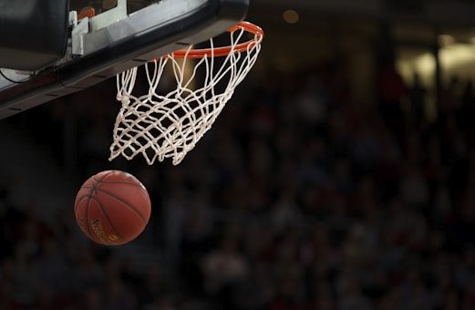 NBA篮球比赛激烈对抗画面，球员腾空投篮，场馆内灯光璀璨气氛热烈